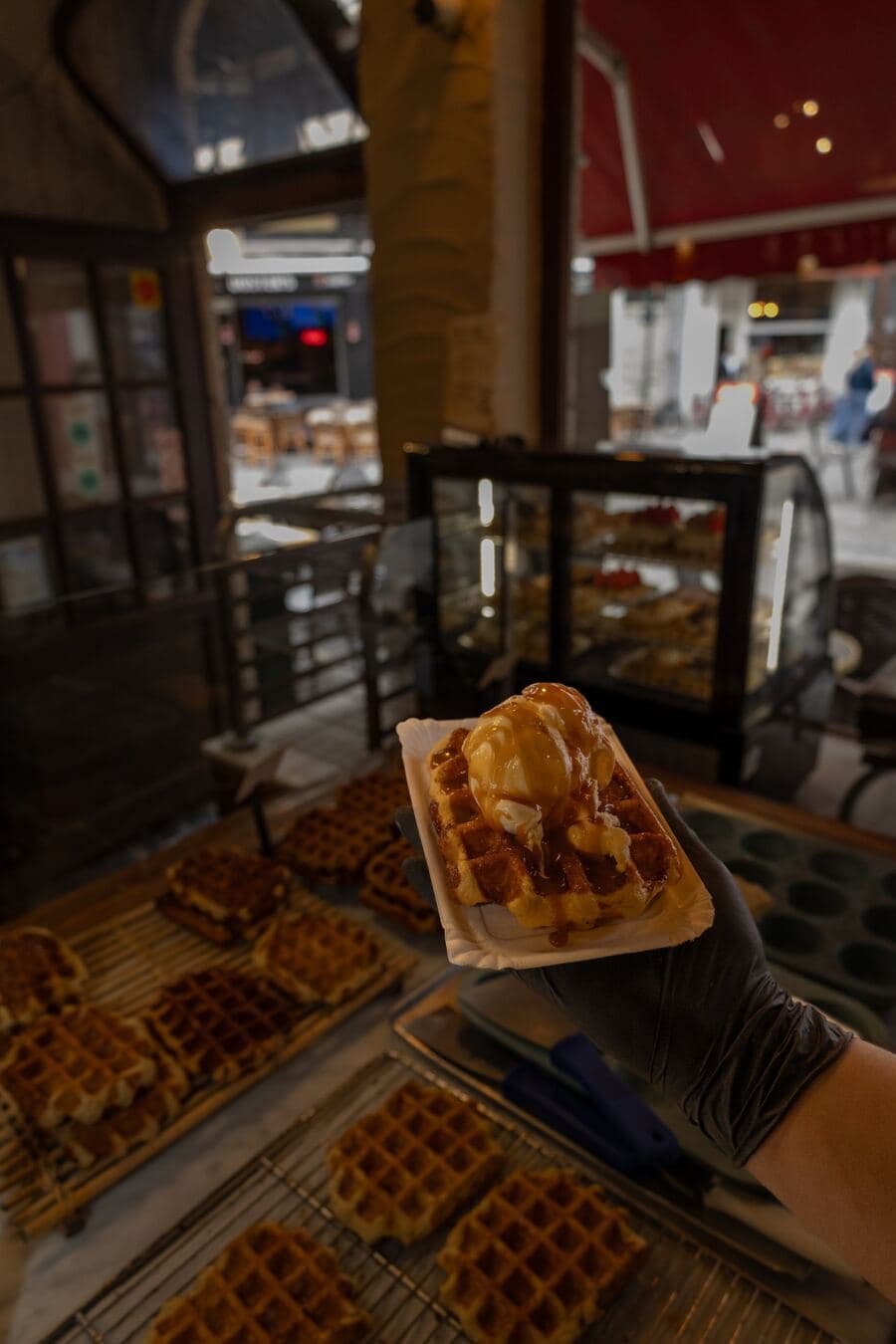 A Liège waffle topped with a scoop of vanilla ice cream and caramel sauce at Le Roi de la Gaufre
